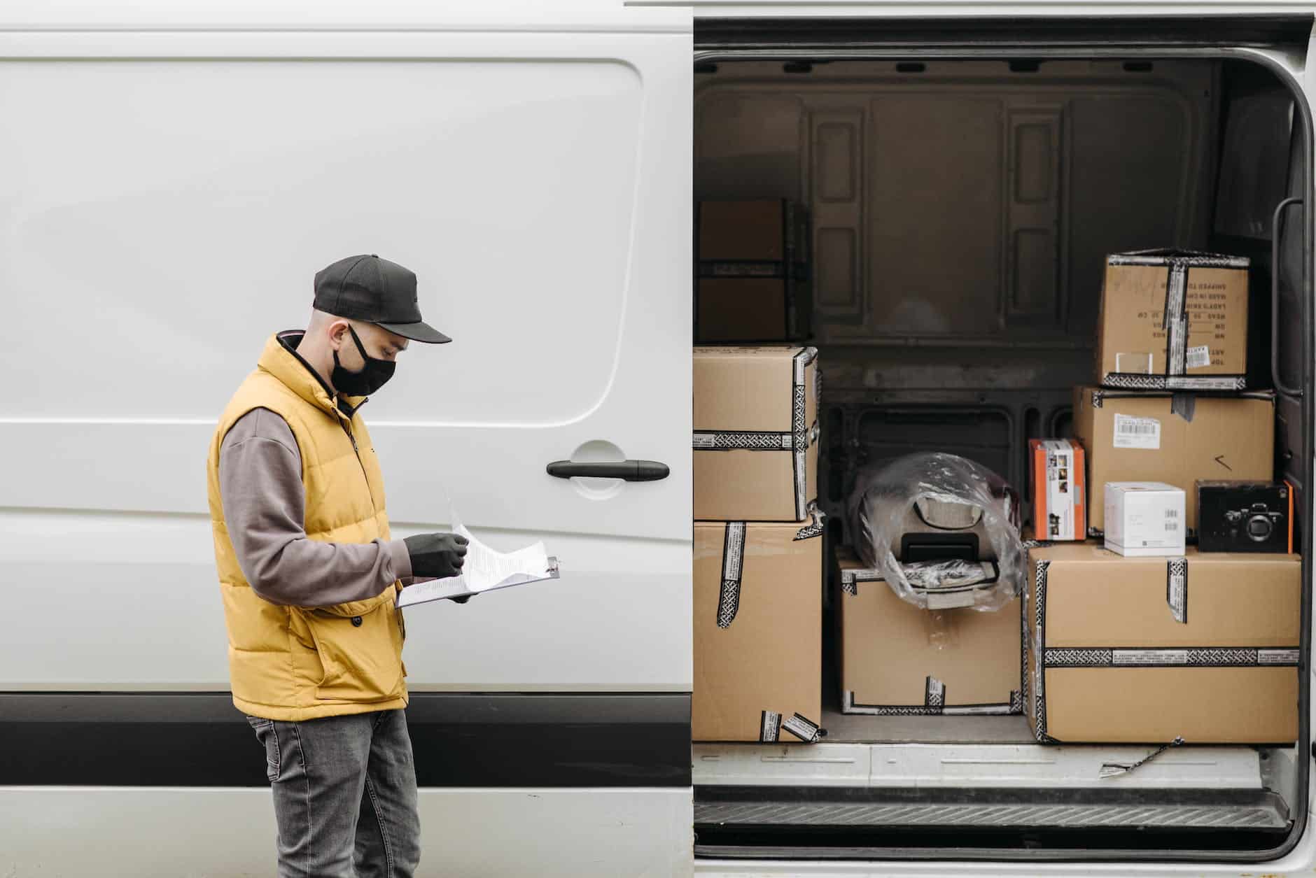 man wearing face mask standing near vehicle door with brown carton boxes